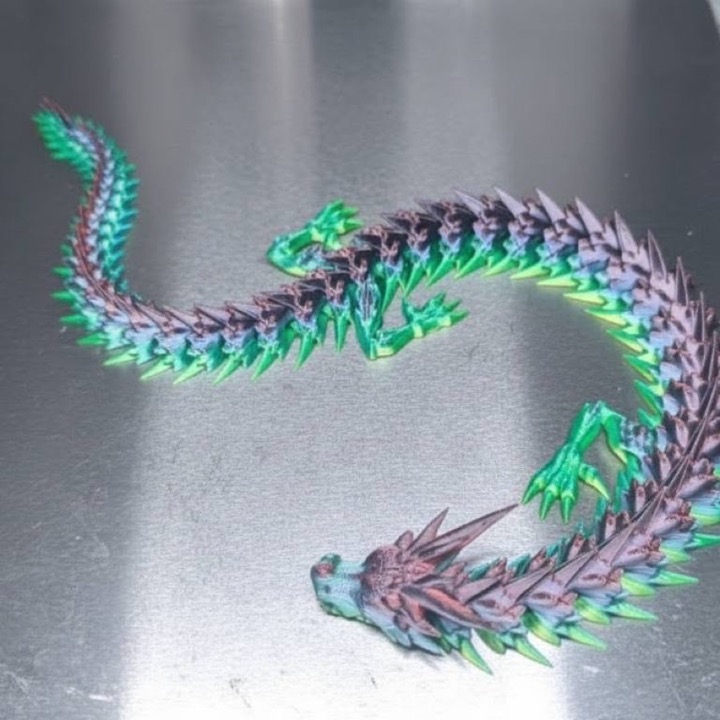 3D printed articulated dragon in shimmering green and purple, coiled on the print bed