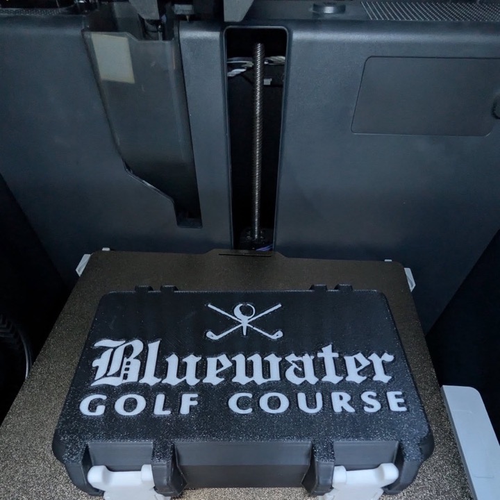 3D printed hinged case holding six yellow golf balls, sitting on the printer bed