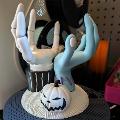 3D printed Halloween holder with skeleton hands and a carved pumpkin