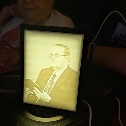 Backlit 3D printed lithophane portrait of a man in a suit, standing in a black frame