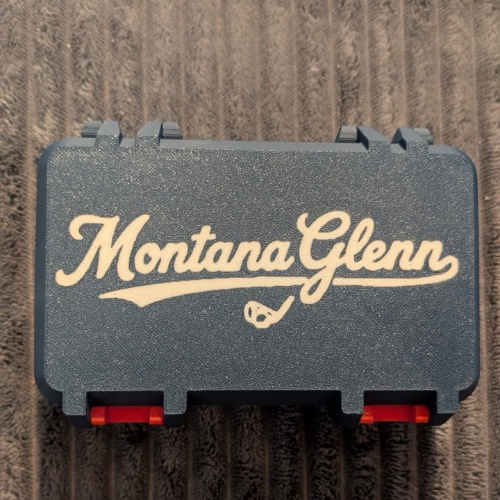 3D printed dark hinged case with a script name across the lid in two-tone lettering