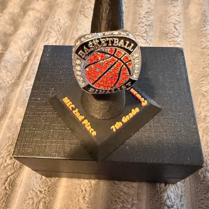 3D printed black display stand holding a youth basketball championship ring, with team and placing text