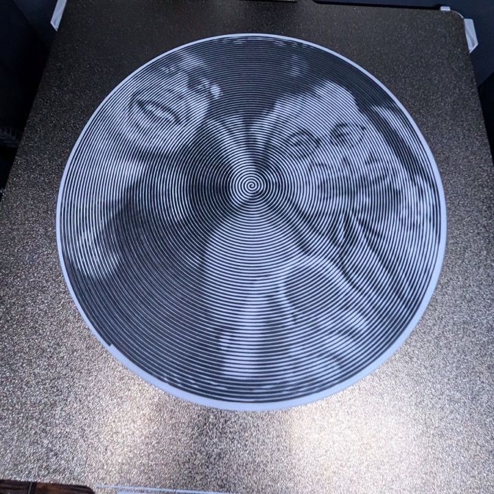 3D printed round plaque with a photo of two people rendered as a single spiral line
