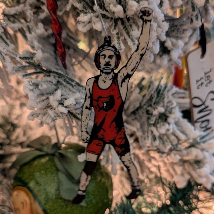 3D printed Christmas ornament of a wrestler raising an arm, hanging on a tree